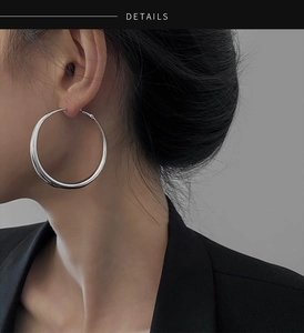 Vue de profil d'un mannequin portant de grandes créoles argentées minimalistes pour femme