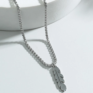 Minimalist stainless steel feather pendant necklace with box chain on a white platform