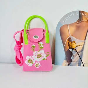 Pink knit floral crossbody phone bag with green resin handles and white flower pattern