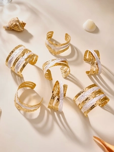 Détail de bracelets joncs en acier plaqué or 18k avec texture martelée et émail blanc