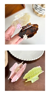 Detail view of shell-shaped acetate hair claw clips with small rhinestone flowers