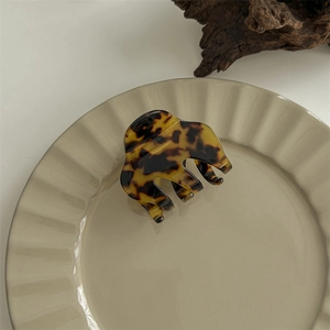 Close-up of tortoise shell pattern claw clip on a ceramic plate with wooden background