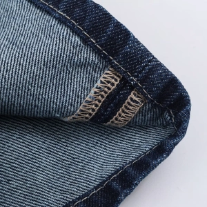 Gros plan détaillé du tissu denim bleu foncé montrant les coutures doubles renforcées