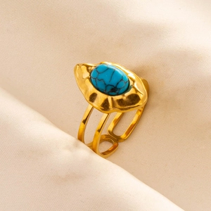 Close-up of bohemian gold ring featuring an oval turquoise stone with textured band
