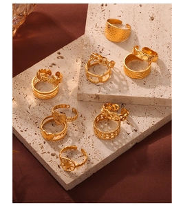 Close-up of tiered gold titanium rings with various textures on beige stone pedestals