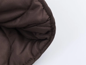 Détail macro du tissu matelassé marron foncé avec couture et passepoil de précision