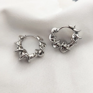Silver twisted spiral hoop earrings with sleek metallic finish on white satin fabric