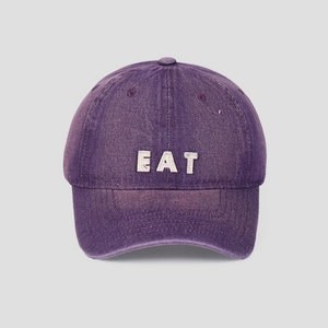 Detailed close-up of washed purple cotton baseball cap with white EAT embroidery