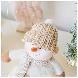 Detail of Christmas snowman plush with sequined knit hat and scarf in warm home setting