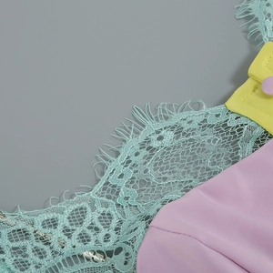 Detail of eyelash lace trim and fabric covered buttons on a pastel slit dress
