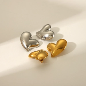 Détail de boucles d'oreilles cœur bombé en finitions or et argent polies avec ombres élégantes