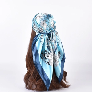 Detail of floral printed satin scarf with white lilies and navy blue border on a model head