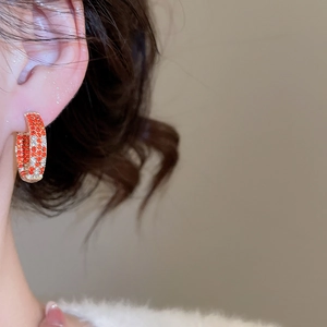 Macro side view of a wide metal hoop earring with red and white crystal inlay