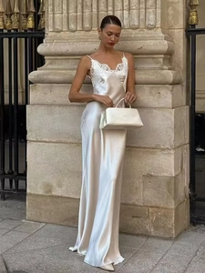 Detail of white satin maxi dress featuring intricate lace patchwork on the neckline