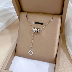 Détail d'un collier lariat argenté avec pendentif cylindre en cristal dans son écrin