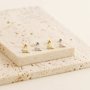 Macro shot of gold and silver spike screw back earrings with crystals on a stone base