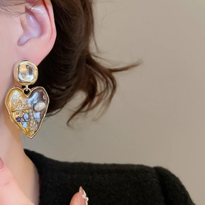 Close-up of vintage heart pearl earring on model showcasing intricate gold details