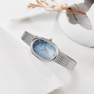 Detailed macro view of an oval light blue mother-of-pearl watch face with silver mesh band