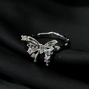 Detailed macro view of silver butterfly ring with colorful gemstones on textured band