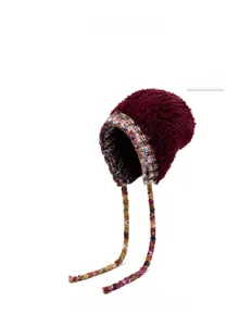 Détail du bonnet en peluche bordeaux avec liens tressés colorés et fourrure douce