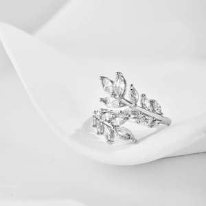 Macro detail of leaf branch ring with sparkling marquise-cut zircon stones on white surface