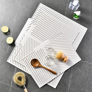 Three grey rectangular silicone drying mats with ribbed design on stone countertop