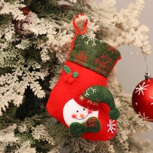 Close-up of a red plush snowman Christmas stocking with festive berries on a snowy branch