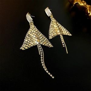 Macro detail of golden fishtail tassel earrings with rhinestones on black leather