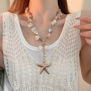 Detail shot of a beaded baroque pearl necklace with gold starfish and shell pendants
