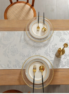 Detail of light grey floral jacquard table runner on a natural wooden dining table surface