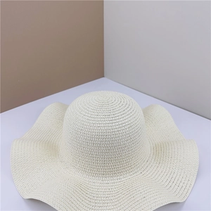 Detail of hand-woven beige straw sun hat with stylish wavy brim for summer beach protection