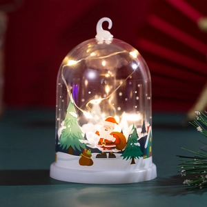 Detail of Santa Claus and snow-covered tree inside a glowing LED Christmas snow globe