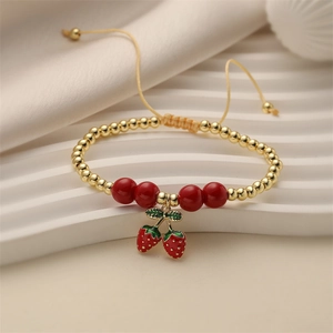Adjustable woven rope bracelet with gold beads and a red strawberry enamel pendant