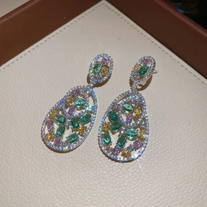 Detailed macro view of silver earrings featuring colorful zircon stones in a teardrop shape