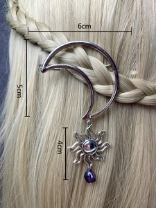Detail of silver crescent moon hair clip with sun charm and purple stone on golden hair
