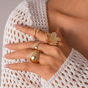 Detailed close-up of a three-piece gold geometric floral ring set on a knit sleeve background