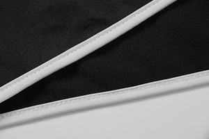 Detailed close-up of premium black fabric with white contrast piping and precise stitching