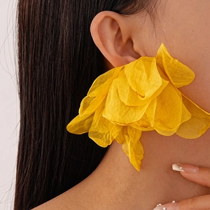 Detailed close-up of large yellow fabric flower earrings with soft layered petals