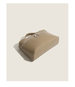 Detail of khaki pebbled leather texture on luxury handbag with silver zipper closure