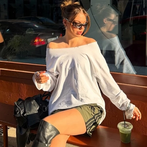 Detail of off-shoulder long sleeve top in white and olive green side-striped shorts