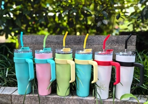 Outdoor lineup of 40oz insulated stainless steel tumblers with handles and straws in six colors