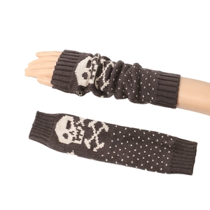 Close-up of brown acrylic knitted arm warmer featuring white skull patterns and polka dots