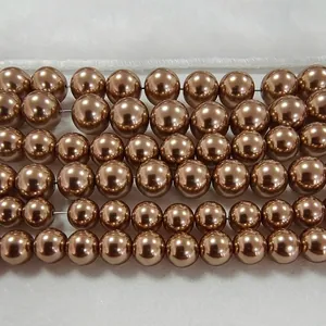 Perles de verre cristal marron café pour bijoux DIY, disposées sur un tissu blanc doux