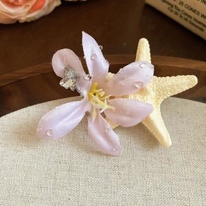 Detailed close-up of pink fabric flower hair clip with crystal butterfly and clear beads