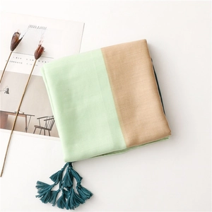 Detail of color-block scarf with light green and brown fabric and dark blue tassels