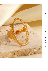Detailed view of golden oval ring with hammered texture on a marble surface