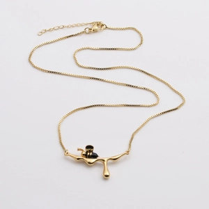 Collana a catena dorata con ciondolo a forma di ape dettagliata su un ramo sottile