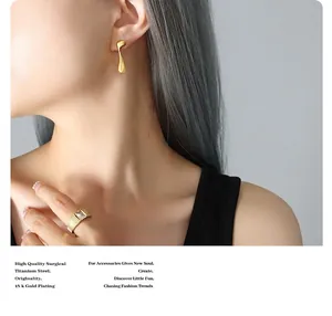 Dettaglio di orecchini in titanio placcati oro 18K e anello con gemma su modella