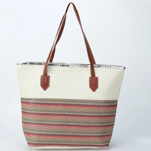 Detail of multi-color striped straw tote bag with brown handles and silver trim