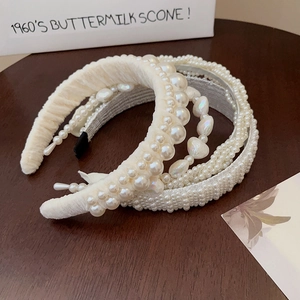 Detailed view of four assorted pearl headbands in elegant creamy white on a wooden desk